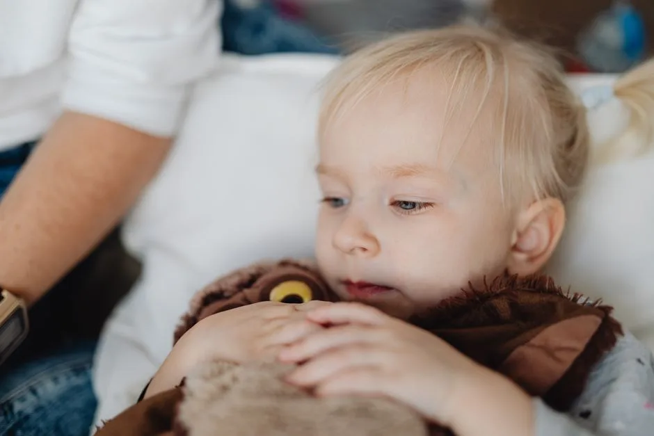 A blonde child holding a plush toy, highlighting innocence and cuteness.