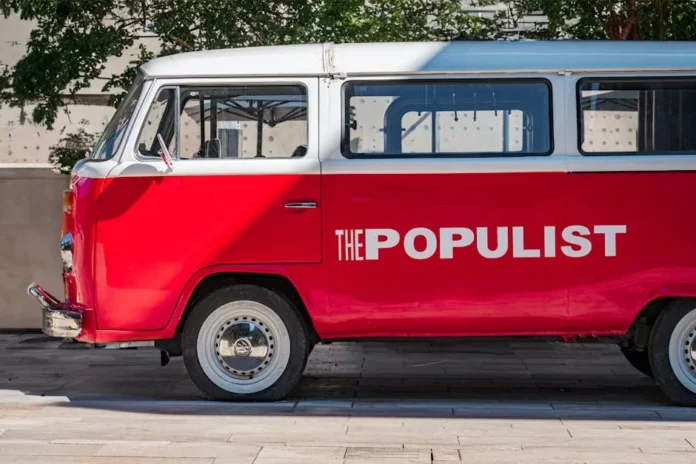 Side view of a vintage red Volkswagen bus parked outdoors in daylight.
