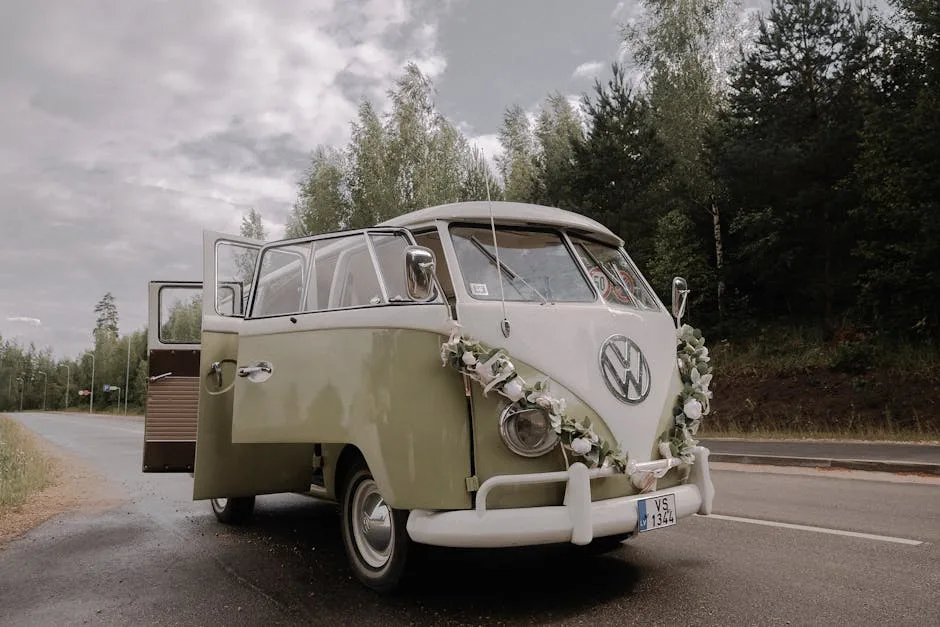 A vintage Volkswagen van adorned with flowers parked on a scenic road, surrounded by nature.