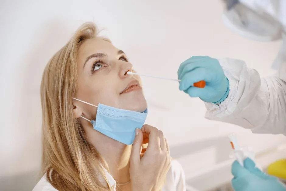 Medical professional performing a COVID-19 nasal swab test on a patient wearing a face mask.